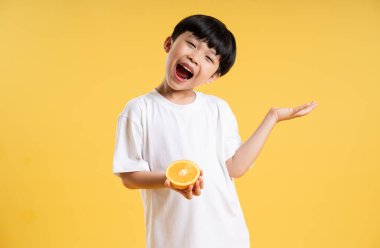 Sarı arka planda poz veren sevimli Asyalı çocuk portresi.