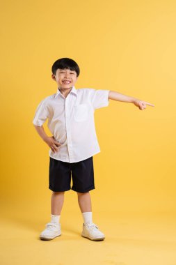Sarı arka planda poz veren sevimli Asyalı çocuk portresi.