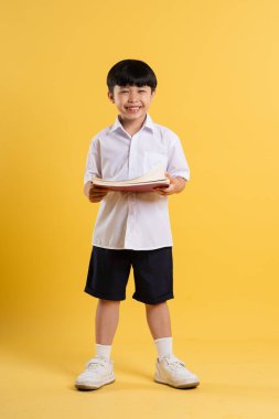 Sarı arka planda poz veren sevimli Asyalı çocuk portresi.