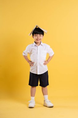 Sarı arka planda poz veren sevimli Asyalı çocuk portresi.