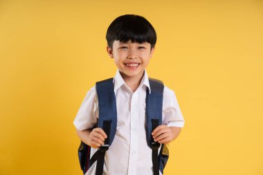 Sarı arka planda poz veren sevimli Asyalı çocuk portresi.