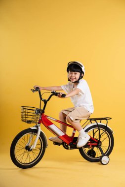 Sarı arka planda poz veren sevimli Asyalı çocuk portresi.