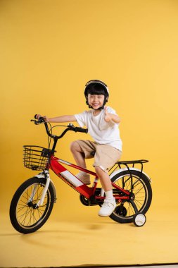 Sarı arka planda poz veren sevimli Asyalı çocuk portresi.