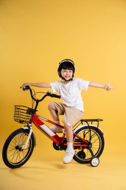 Sarı arka planda poz veren sevimli Asyalı çocuk portresi.