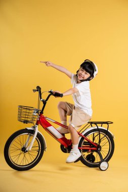 Sarı arka planda poz veren sevimli Asyalı çocuk portresi.