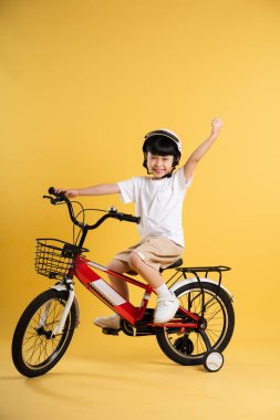 Sarı arka planda poz veren sevimli Asyalı çocuk portresi.