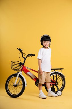Sarı arka planda poz veren sevimli Asyalı çocuk portresi.