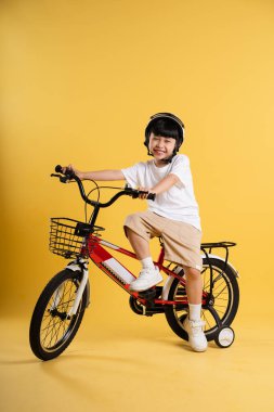 Sarı arka planda poz veren sevimli Asyalı çocuk portresi.