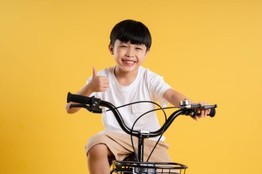 Sarı arka planda poz veren sevimli Asyalı çocuk portresi.