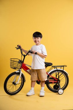 Sarı arka planda poz veren sevimli Asyalı çocuk portresi.