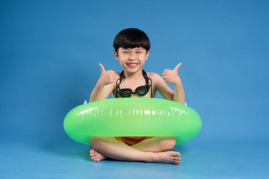 Mavi arka planda poz veren Asyalı çocuk portresi