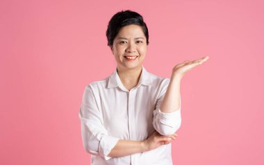 Pembe arka planda poz veren yaşlı Asyalı iş kadını