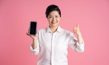 Pembe arka planda poz veren yaşlı Asyalı iş kadını