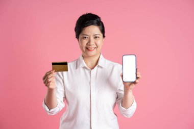 Pembe arka planda poz veren yaşlı Asyalı iş kadını