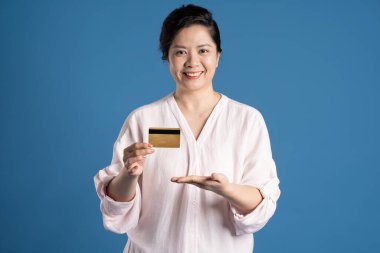 Mavi arka planda poz veren yaşlı Asyalı kadın portresi