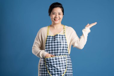 Mavi arka planda poz veren yaşlı Asyalı kadın portresi