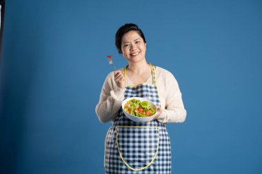 Mavi arka planda poz veren yaşlı Asyalı kadın portresi