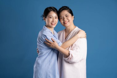 Mavi arka planda poz veren Asyalı bir anne ve çocuğun resmi