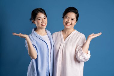 Mavi arka planda poz veren Asyalı bir anne ve çocuğun resmi