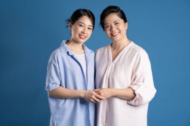 Mavi arka planda poz veren Asyalı bir anne ve çocuğun resmi