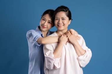 Mavi arka planda poz veren Asyalı bir anne ve çocuğun resmi