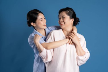 Mavi arka planda poz veren Asyalı bir anne ve çocuğun resmi