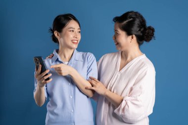 Mavi arka planda poz veren Asyalı bir anne ve çocuğun resmi