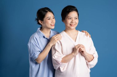 Mavi arka planda poz veren Asyalı bir anne ve çocuğun resmi