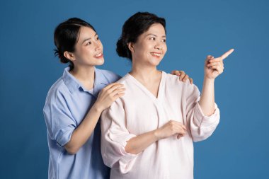 Mavi arka planda poz veren Asyalı bir anne ve çocuğun resmi