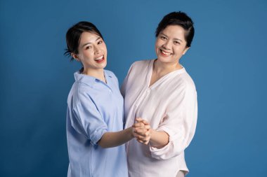 Mavi arka planda poz veren Asyalı bir anne ve çocuğun resmi