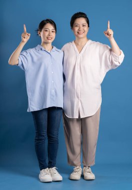 Mavi arka planda poz veren Asyalı bir anne ve çocuğun resmi