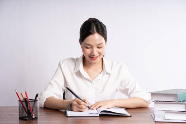 Genç bayan iş adamı beyaz arka planda masada oturuyor.