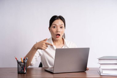 Genç bayan iş adamı beyaz arka planda masada oturuyor.