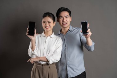 Gri arka planda poz veren Asyalı iş çifti