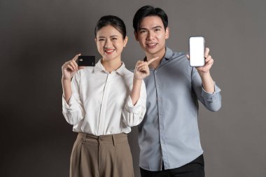 Gri arka planda poz veren Asyalı iş çifti