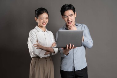 Gri arka planda poz veren Asyalı iş çifti