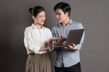 Gri arka planda poz veren Asyalı iş çifti