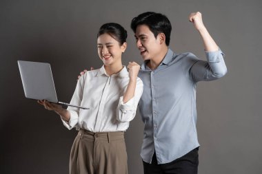 Gri arka planda poz veren Asyalı iş çifti