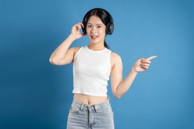 Mavi arka planda poz veren güzel Asyalı kadın portresi