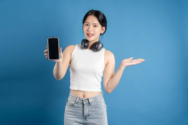 Mavi arka planda poz veren güzel Asyalı kadın portresi