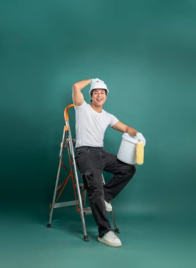 Ressam bir mola veriyor. Gülümseyen adam kask, iş eldiveni, tişört ve koyu renk pantolon giyiyor. Merdiven üzerinde oturmak, DIY konsepti.