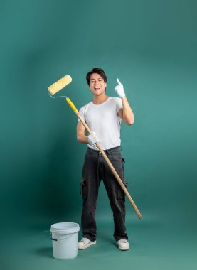 Hevesli bir ressam stüdyo arka planında boya silindiriyle duruyor. Evinizi canlı bir renkle boyamaya ve yaratıcılığa ilham vermeye hazırım..