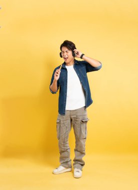 Sarı arka planda poz veren Asyalı adamın portresi