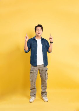 Sarı arka planda poz veren Asyalı adamın portresi