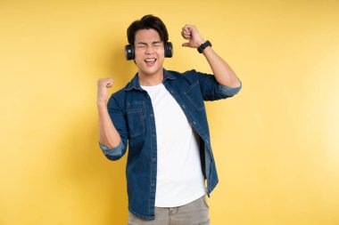 Sarı arka planda poz veren yakışıklı Asyalı adamın portresi.