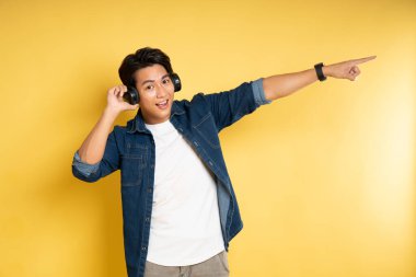 Sarı arka planda poz veren yakışıklı Asyalı adamın portresi.