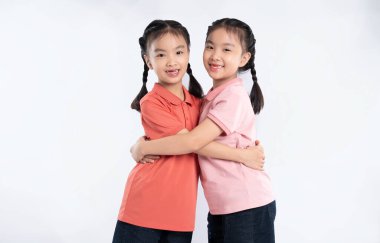 Kardeşliğin sıcacık bir kucaklamasını paylaşan iki genç kız, uyumlu kıyafetleri ve örgüleriyle neşe saçıyor..