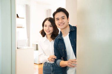 Kapıda bekleyen gülümseyen bir çift insanları evlerinde karşılamaya hazır ve neşeli.