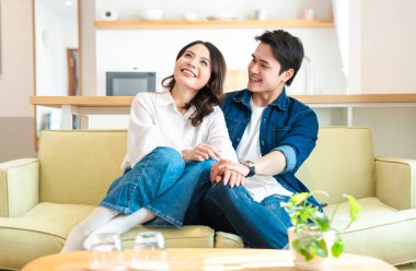 Bir çift, evlerindeki açık yeşil bir kanepede rahatlar. Gülümser ve birlikte sevgi dolu bir anı paylaşırlar.