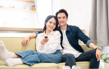 Bir çift, birlikte vakit geçirirken kanepede oturup televizyon seyrediyor.